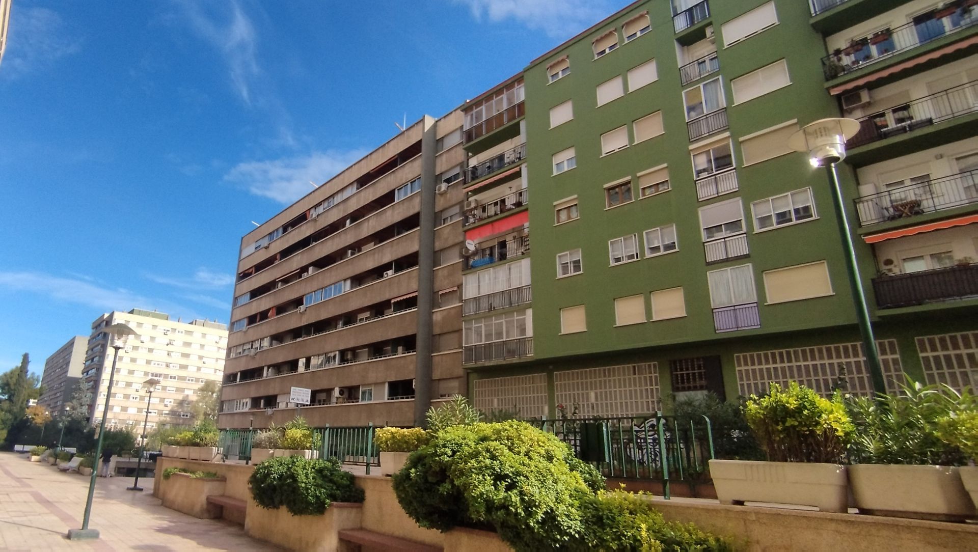 Un edificio de ladrillo con una valla verde delante.
