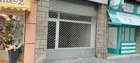 Un escaparate con una persiana cerrada y un toldo amarillo.