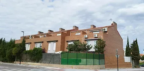 Un edificio de ladrillo con una valla verde delante.