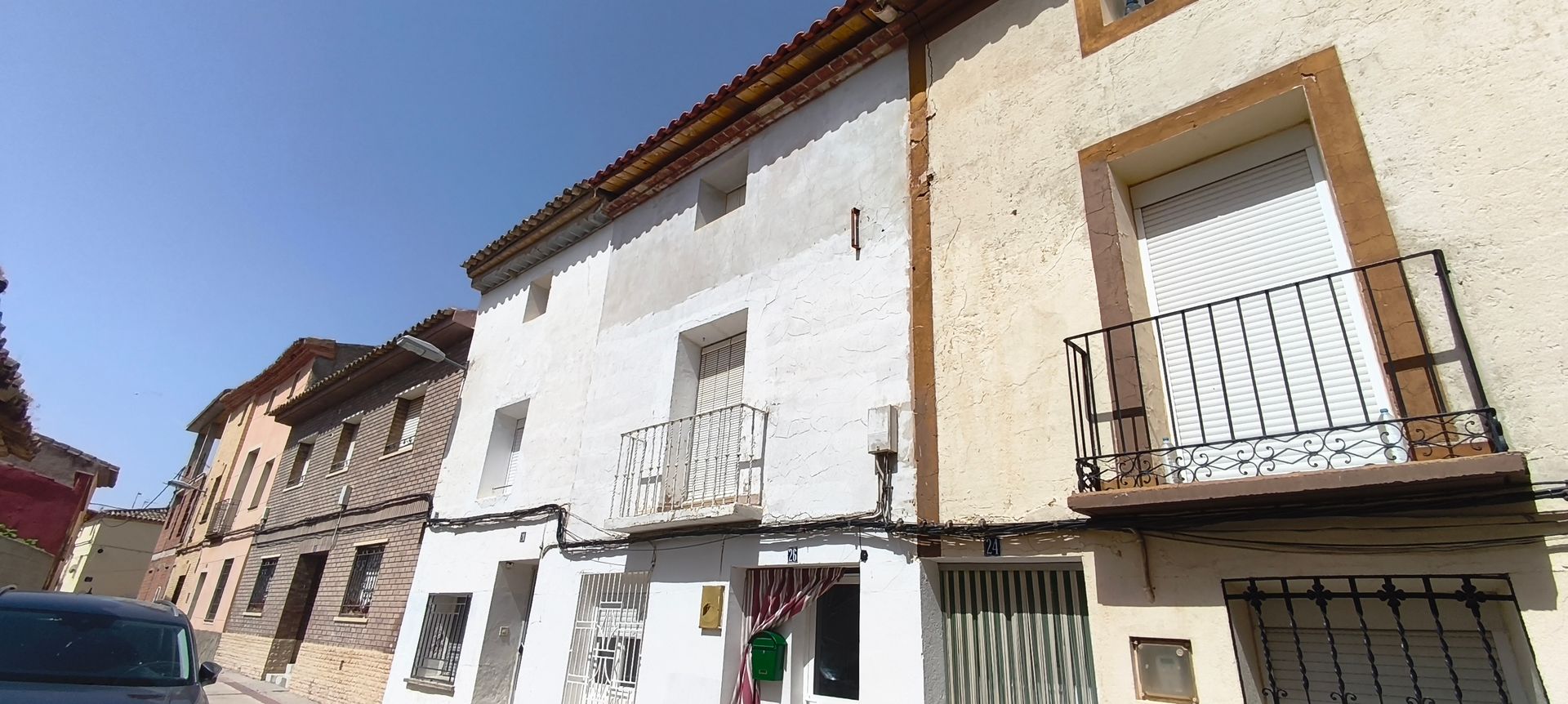 Un frente de tienda con una persiana en la puerta y un cartel en el costado del edificio.