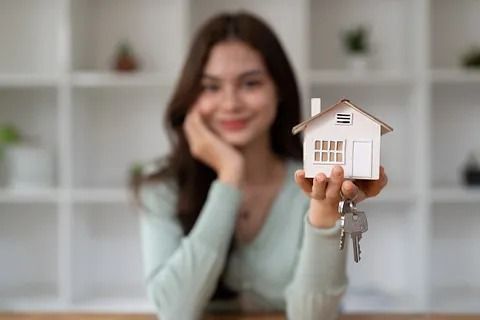 Una mujer sostiene una maqueta de casa y llaves.