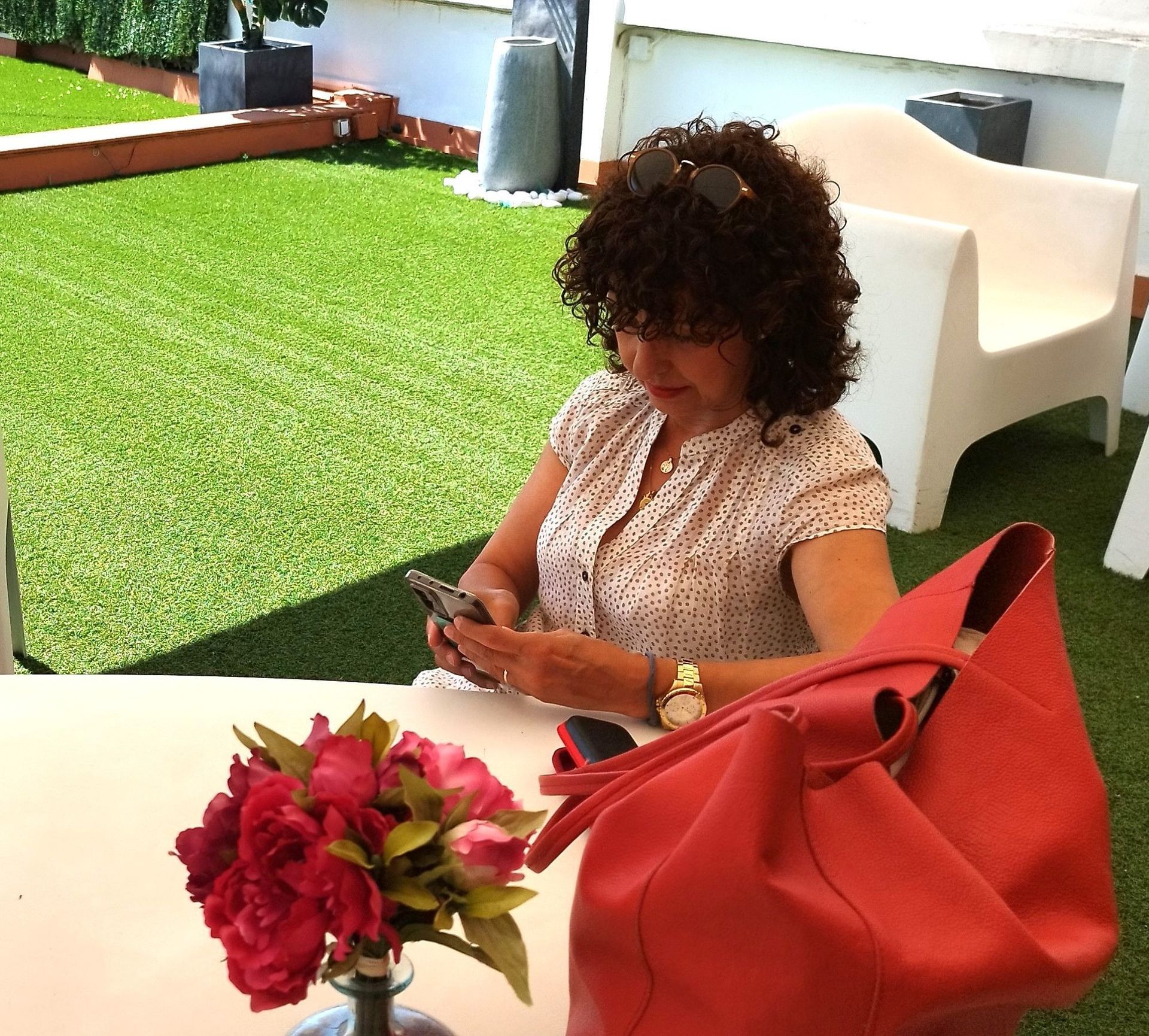 Una mujer está sentada en una mesa mirando su teléfono.