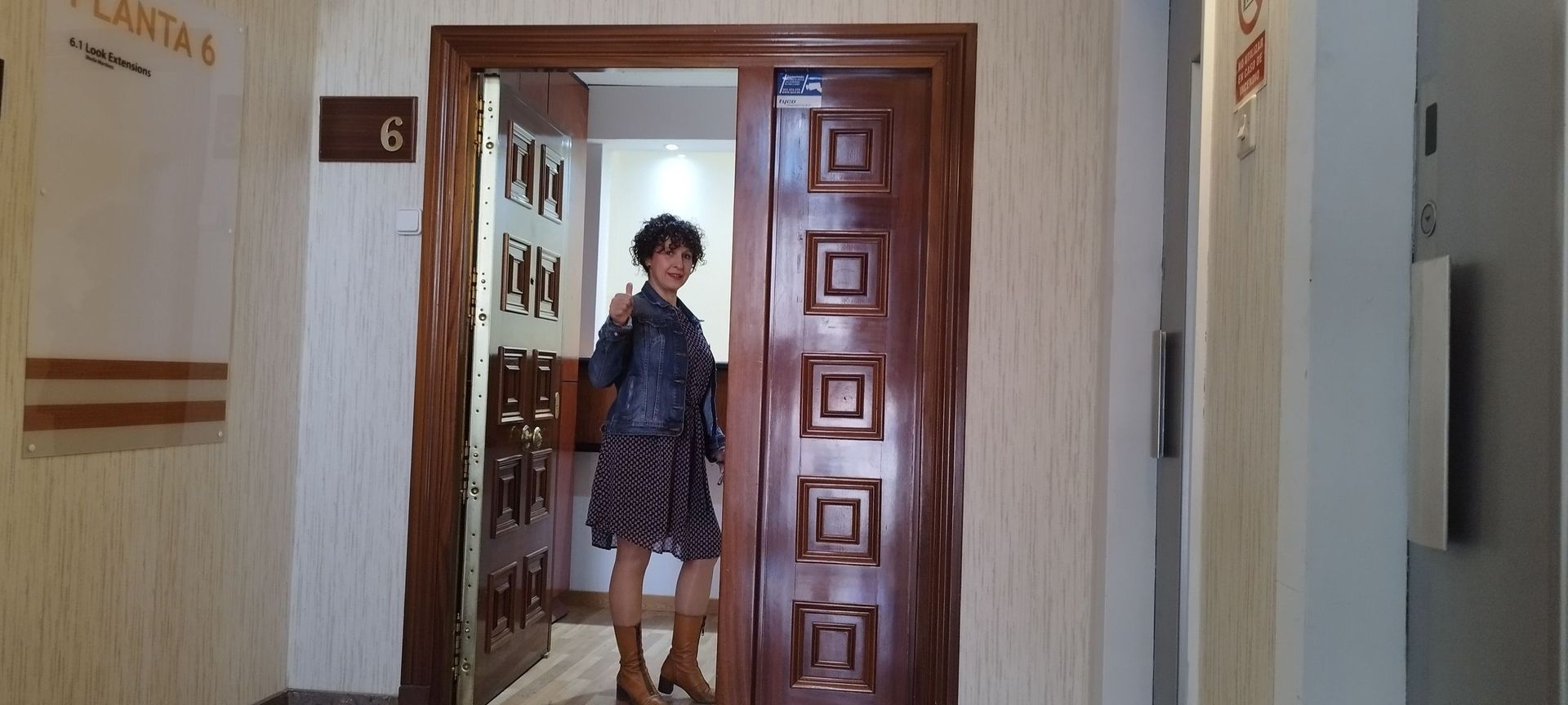 Una mujer está parada frente a una puerta con el número 6 en ella.