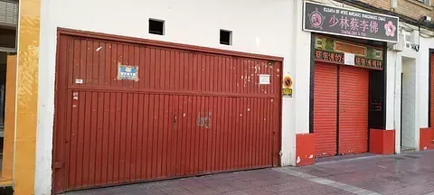 Una puerta de garaje roja está cerrada delante de un edificio.