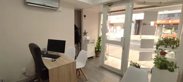 Una habitación con un escritorio y sillas y una computadora encima.