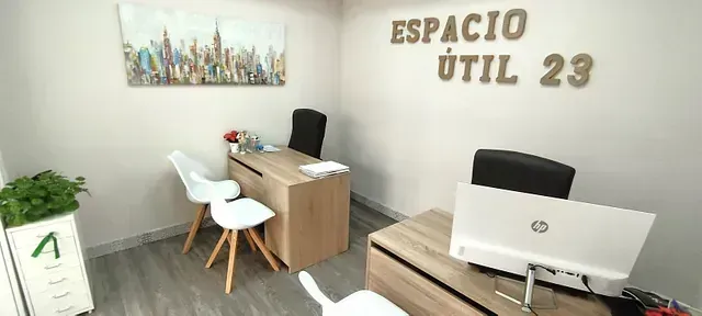 Una pequeña oficina con un escritorio y sillas y un cartel que dice espacio util 23