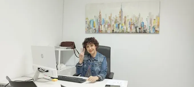 Una mujer está sentada en un escritorio frente a una computadora.
