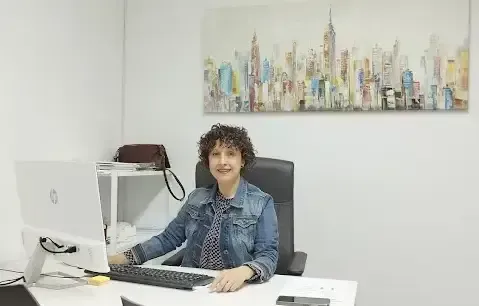 Una mujer está sentada en un escritorio frente a una computadora.