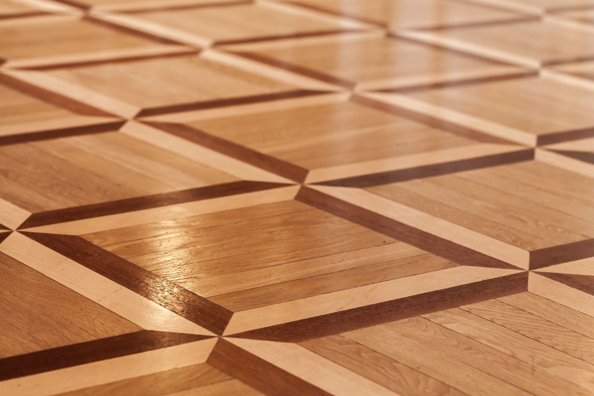 Parquet en bois orné d’un motif géométrique en losanges incrustés et aux reflets chaleureux.