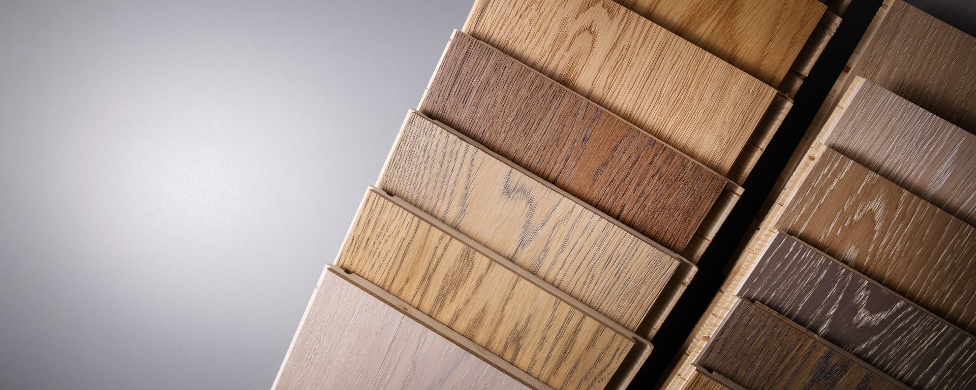 Gros plan sur des lames de parquet imitation bois de différentes teintes, sur un fond gris doux.