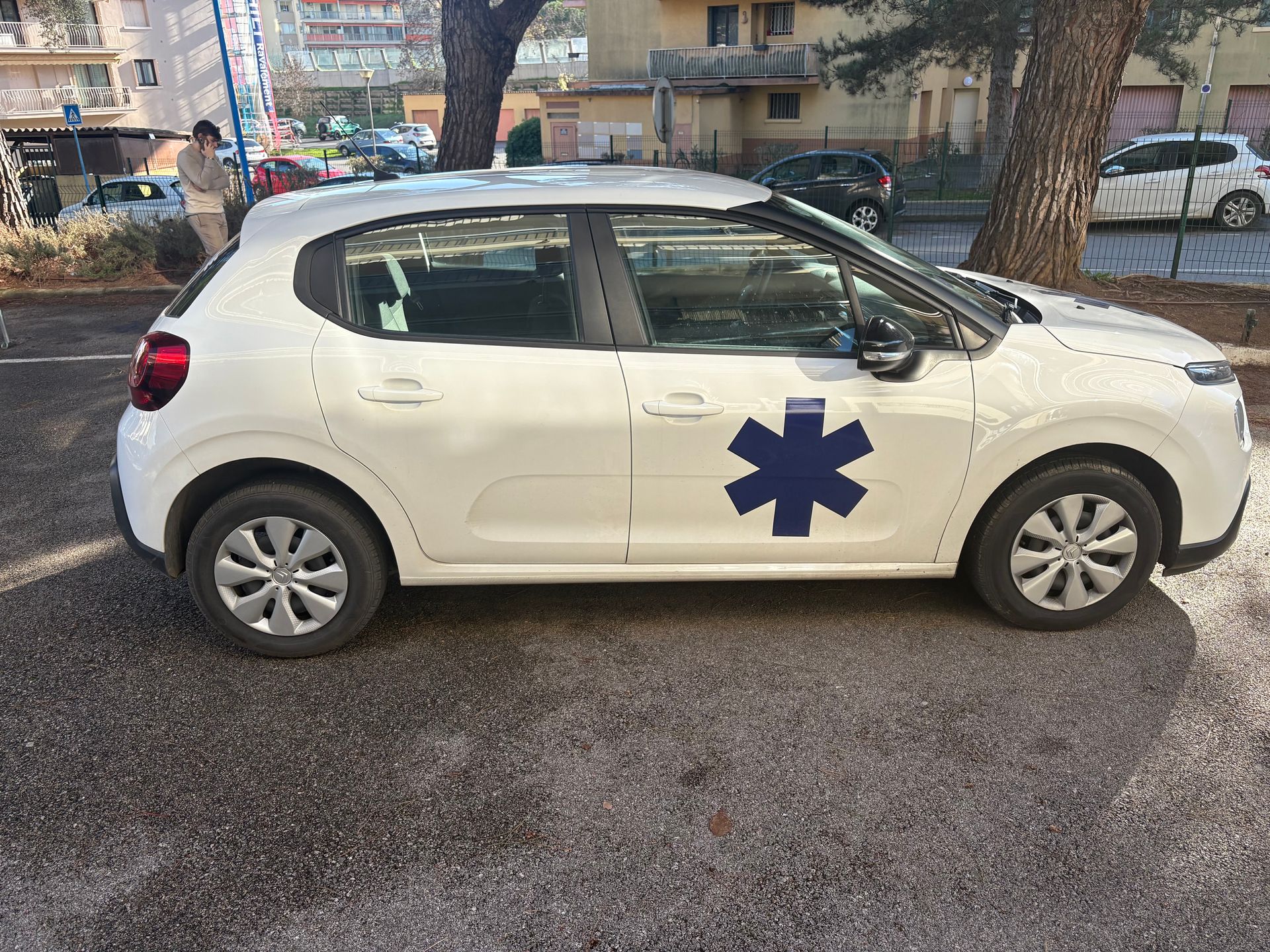 Voiture ornée d'une étoile de vie garée dans la rue ; une personne se tient à proximité.