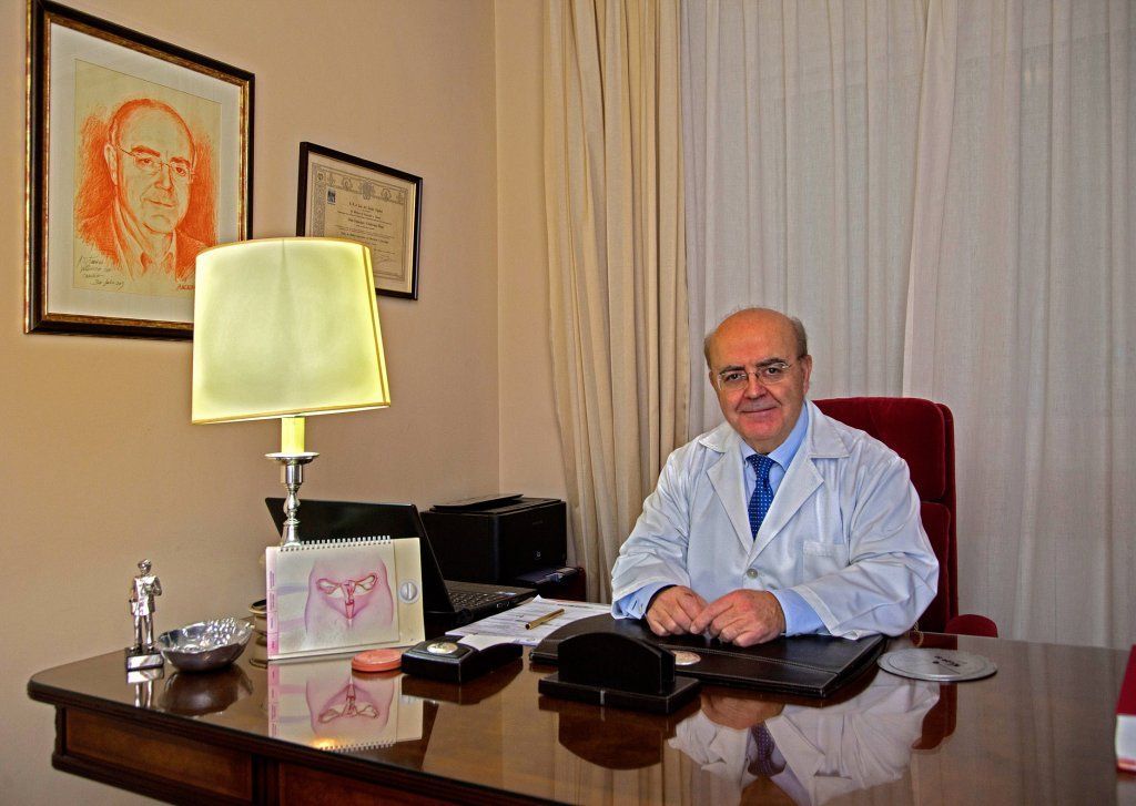 Un hombre con una bata de laboratorio está sentado en un escritorio en una habitación.