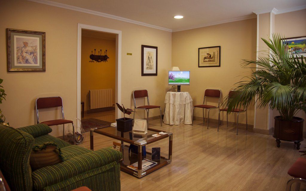 Una sala de estar con sofá, sillas, mesa de café y televisión.