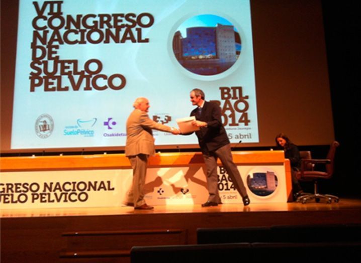 Dos hombres se dan la mano frente a una pantalla que dice VII Congreso Nacional de Suelo Pélvico