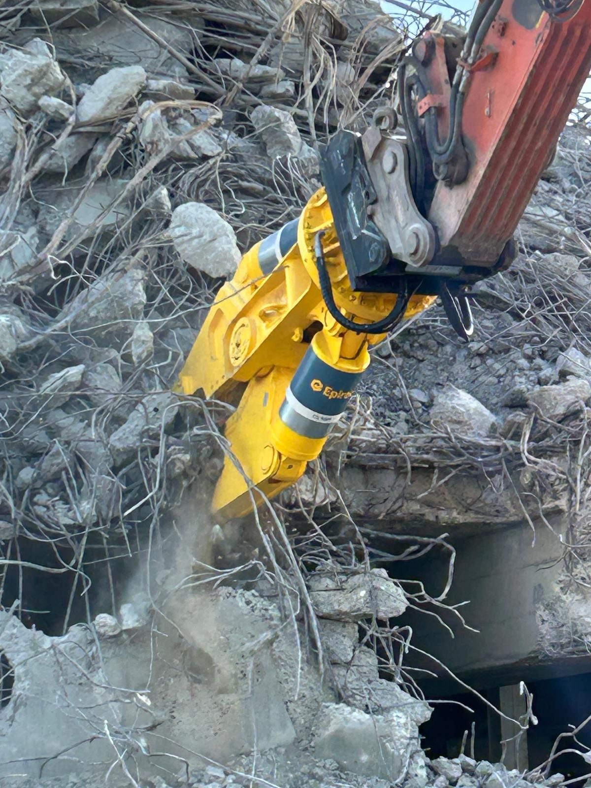 Ein gelber Bagger zerstört ein Gebäude.