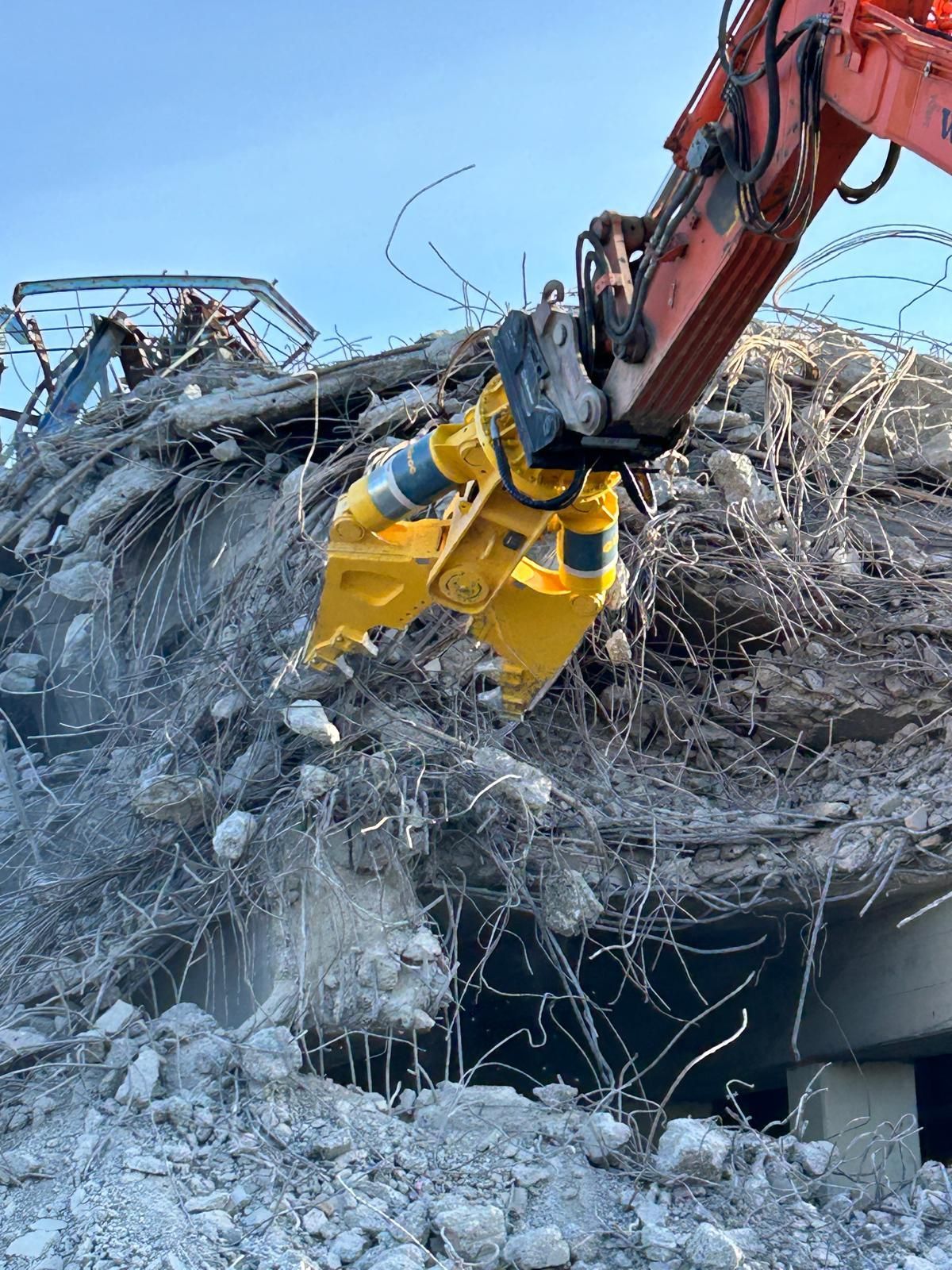 Ein großer gelber Bagger zerstört ein Gebäude.