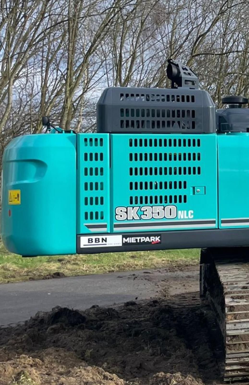 Am Straßenrand parkt ein blau-schwarzer Bagger.
