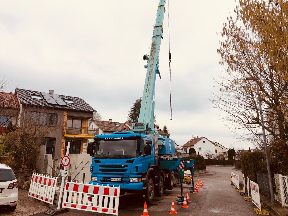 Ein blauer Lastwagen mit einem daran befestigten Kran steht am Straßenrand.