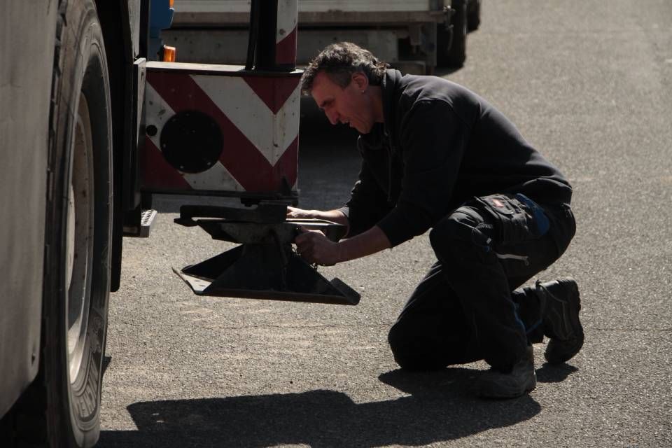 Ein Mann kniet nieder, um einen Reifen an einem Lastwagen zu reparieren.