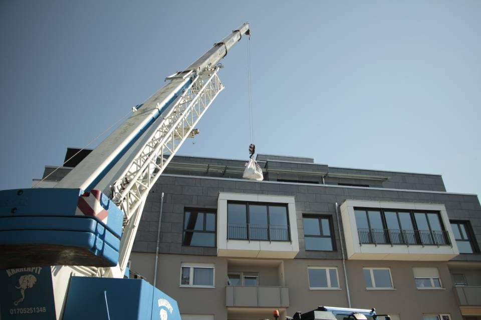 Ein blau-weißer Kran steht vor einem Gebäude