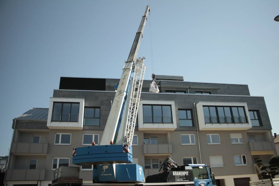 Ein großer blauer Kran steht vor einem Gebäude