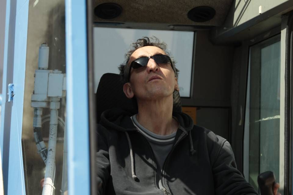 Ein Mann mit Sonnenbrille sitzt in einer blauen Kabine