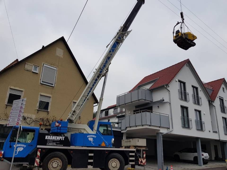 Ein Kran hebt ein gelbes Objekt vor einem Gebäude