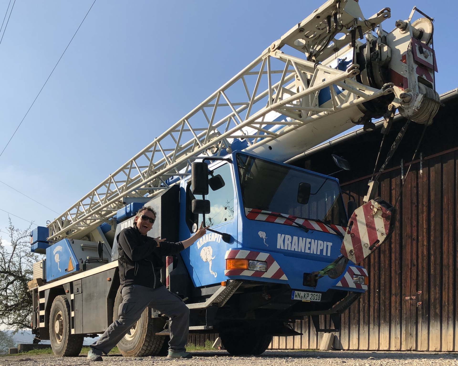 Ein Mann steht vor einem Kran, auf dem Kranenpit steht