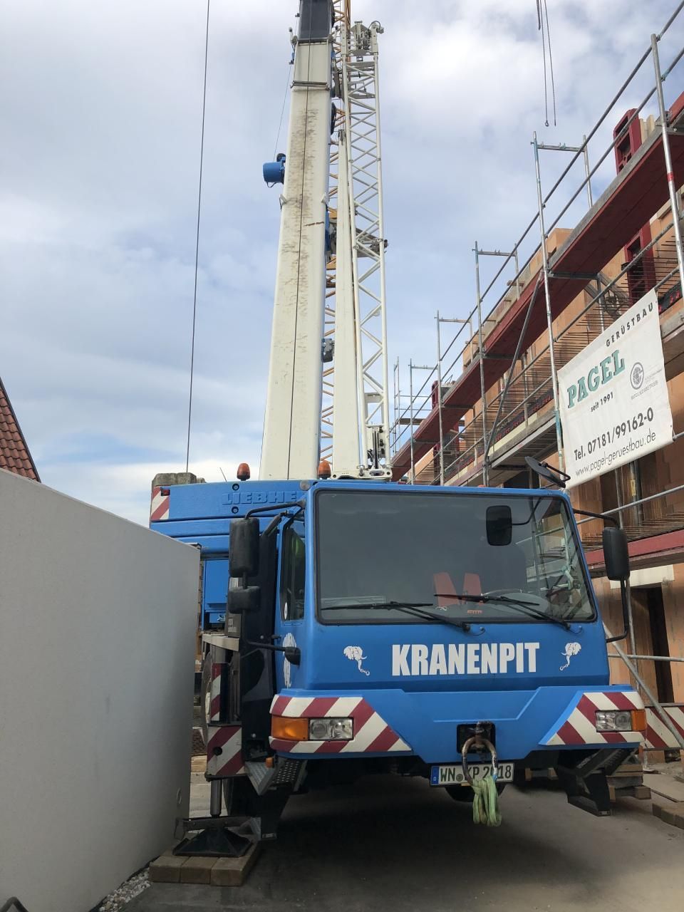 Ein blauer Kranenpit-LKW steht vor einem Gebäude