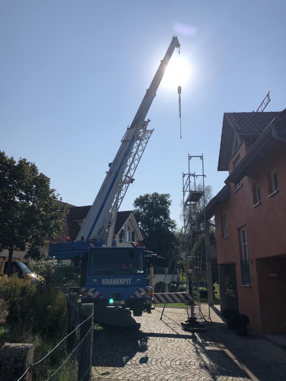 Ein Kran hebt etwas vor einem Haus