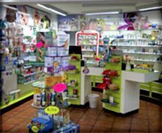 El interior de una farmacia con mostradores verdes, diversos productos en los estantes y suelo de baldosas.