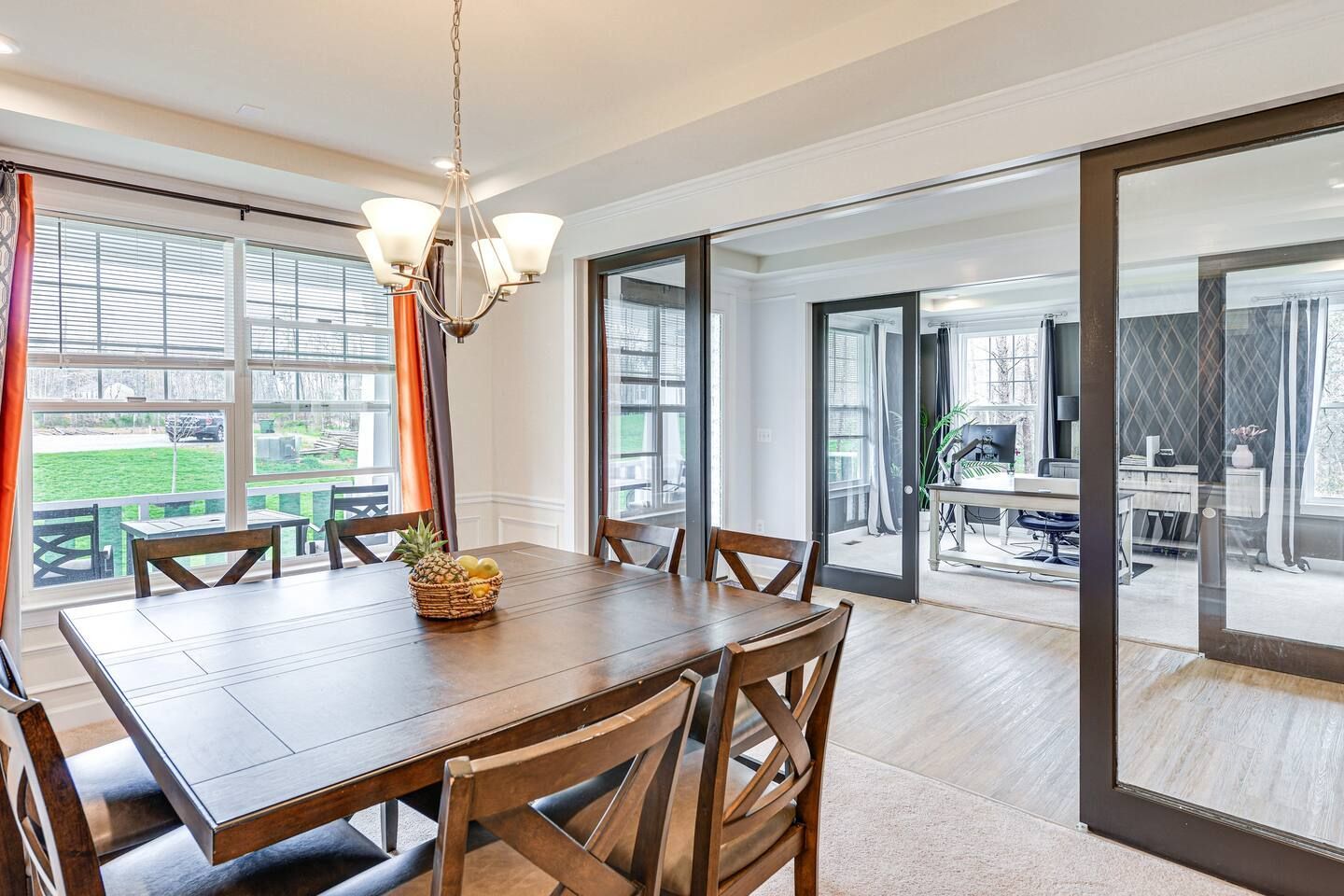 A dining room with a table and chairs and a large mirror.