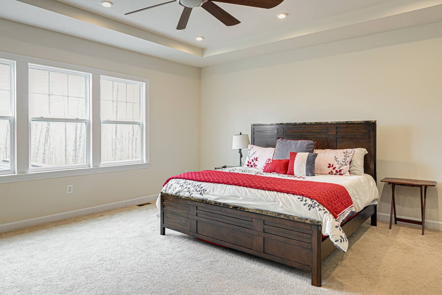A bedroom with a king size bed , a ceiling fan , and two windows.