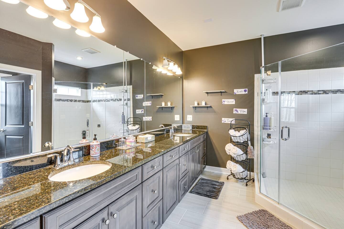 A bathroom with two sinks , a shower and a large mirror.