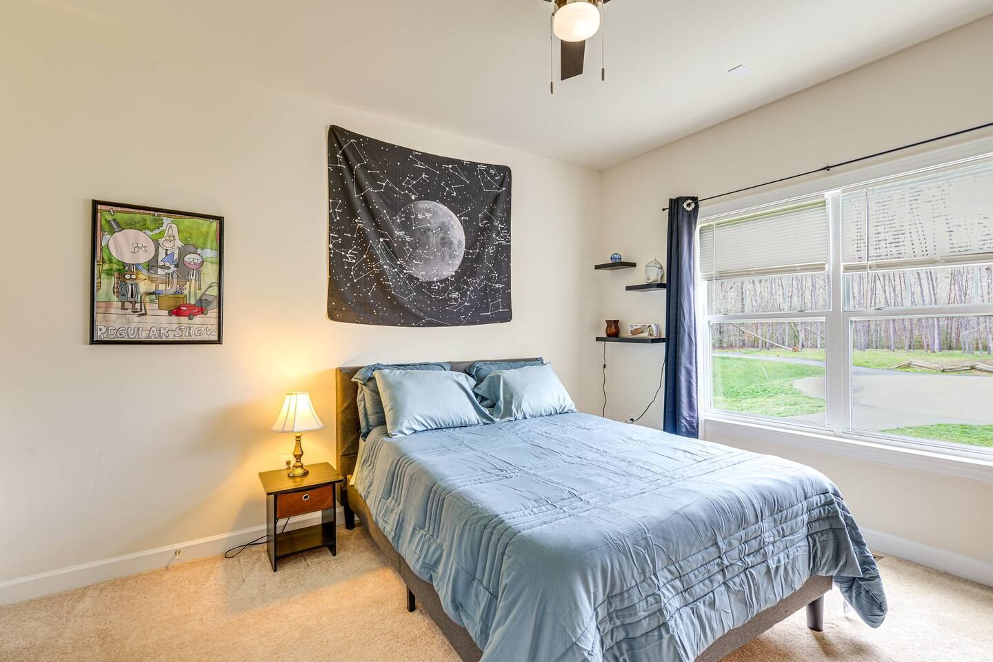 A bedroom with a bed , nightstand , lamp and a ceiling fan.
