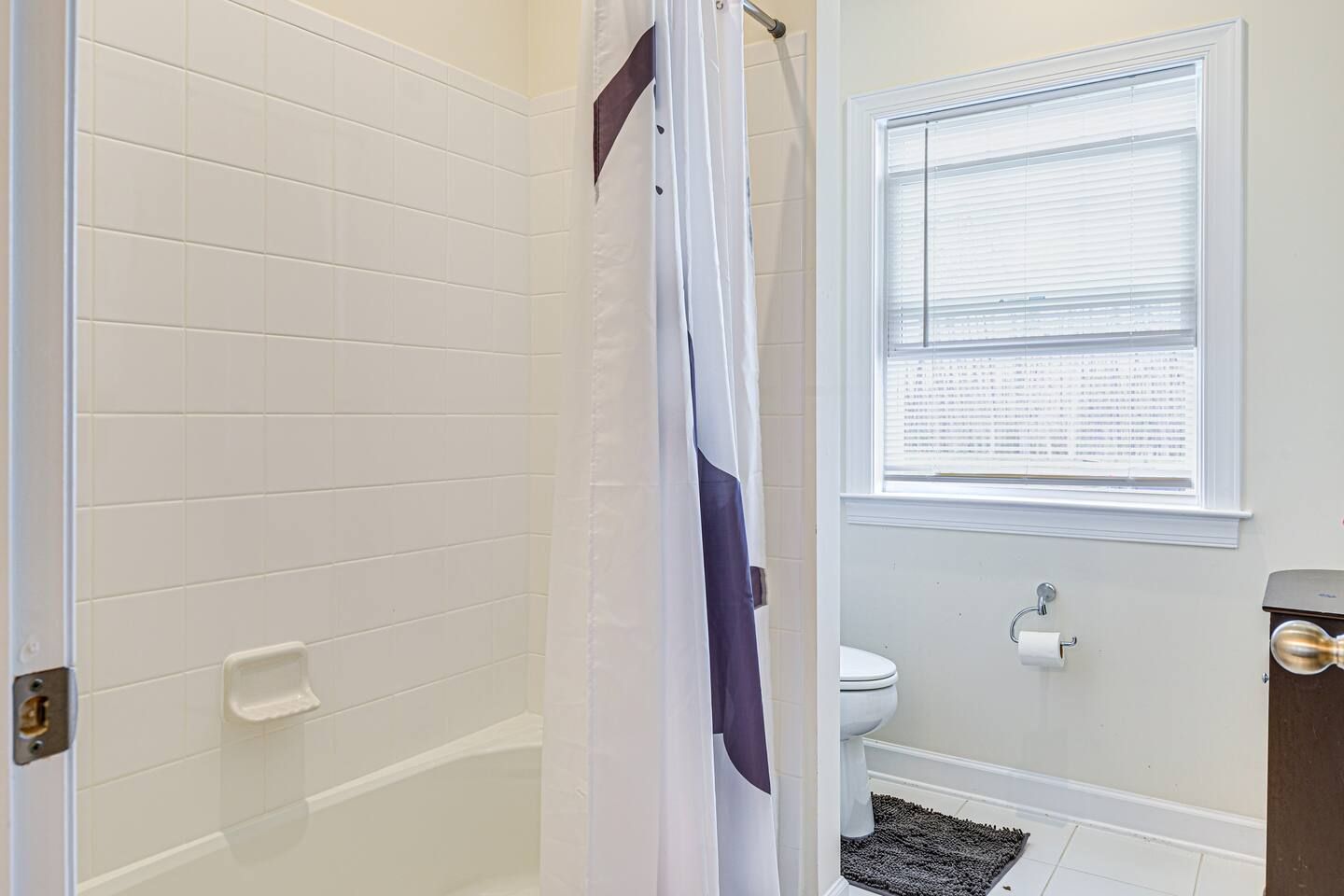 A bathroom with a shower , toilet , and window.