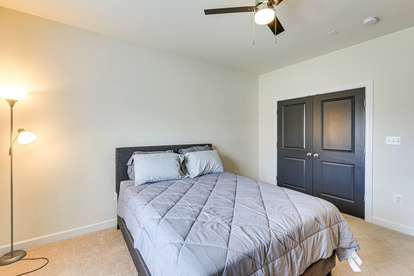 A bedroom with a bed , lamp and ceiling fan.