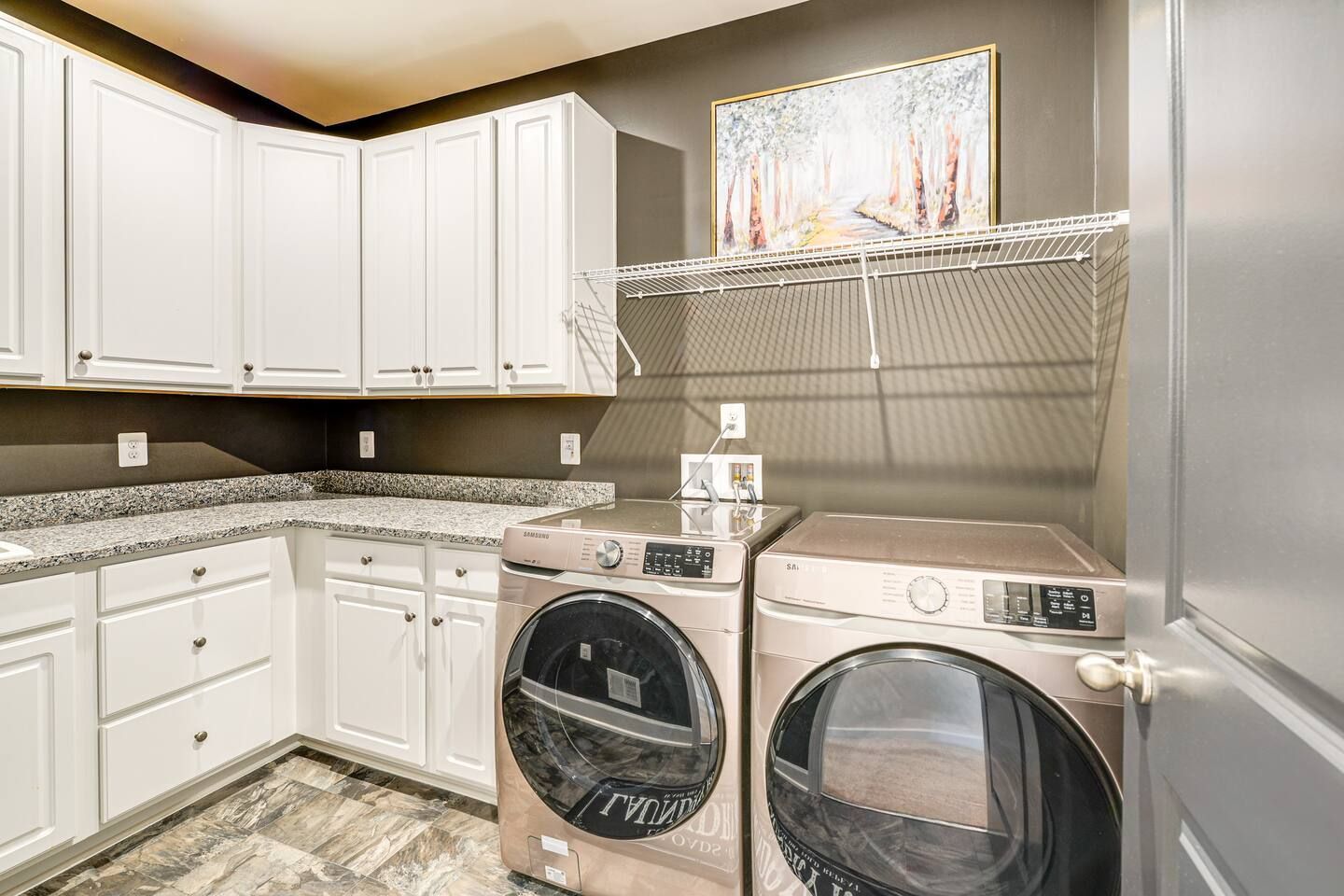 A laundry room with a washer and dryer and white cabinets.