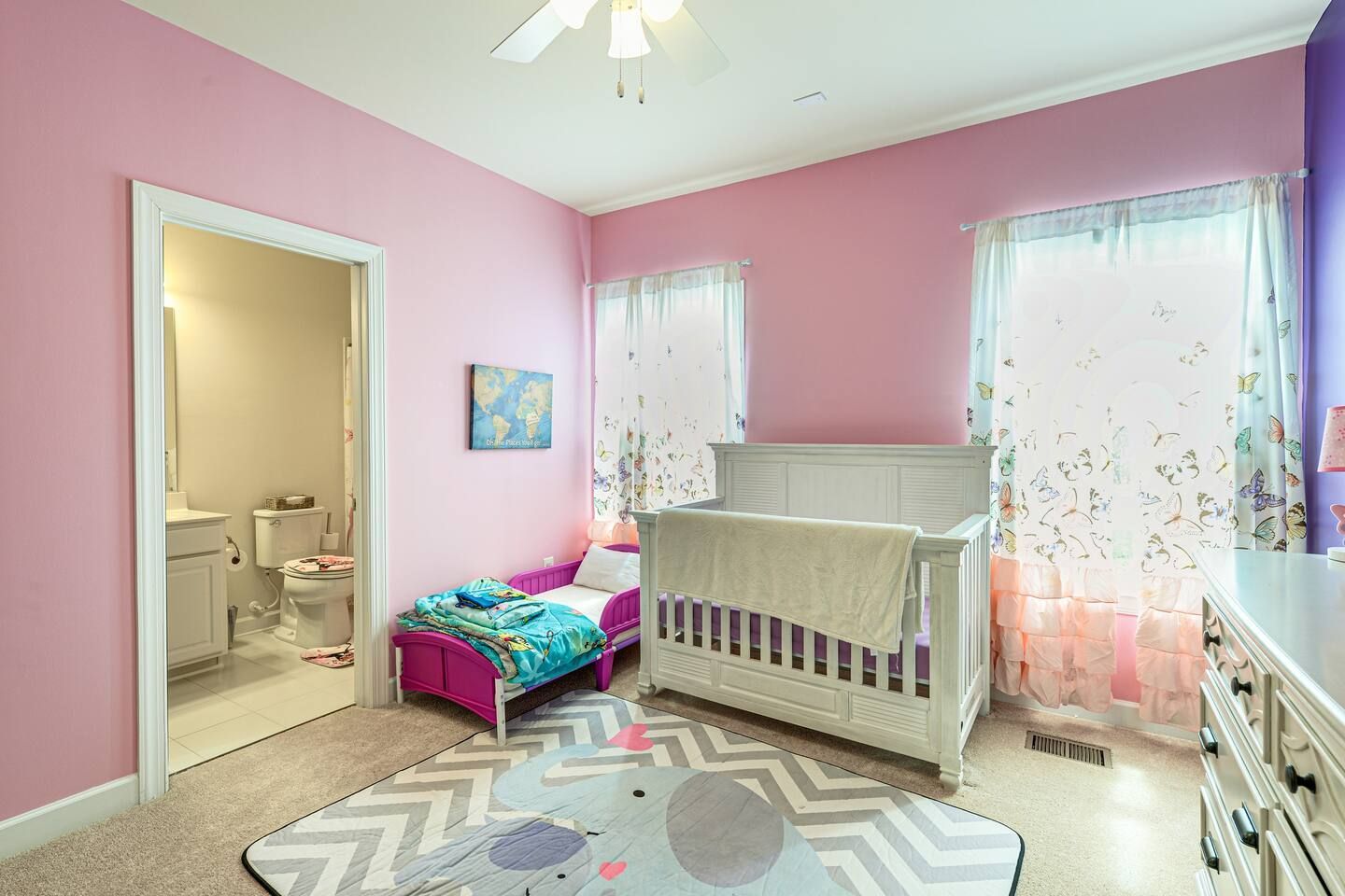 A child 's bedroom with pink walls and a crib.
