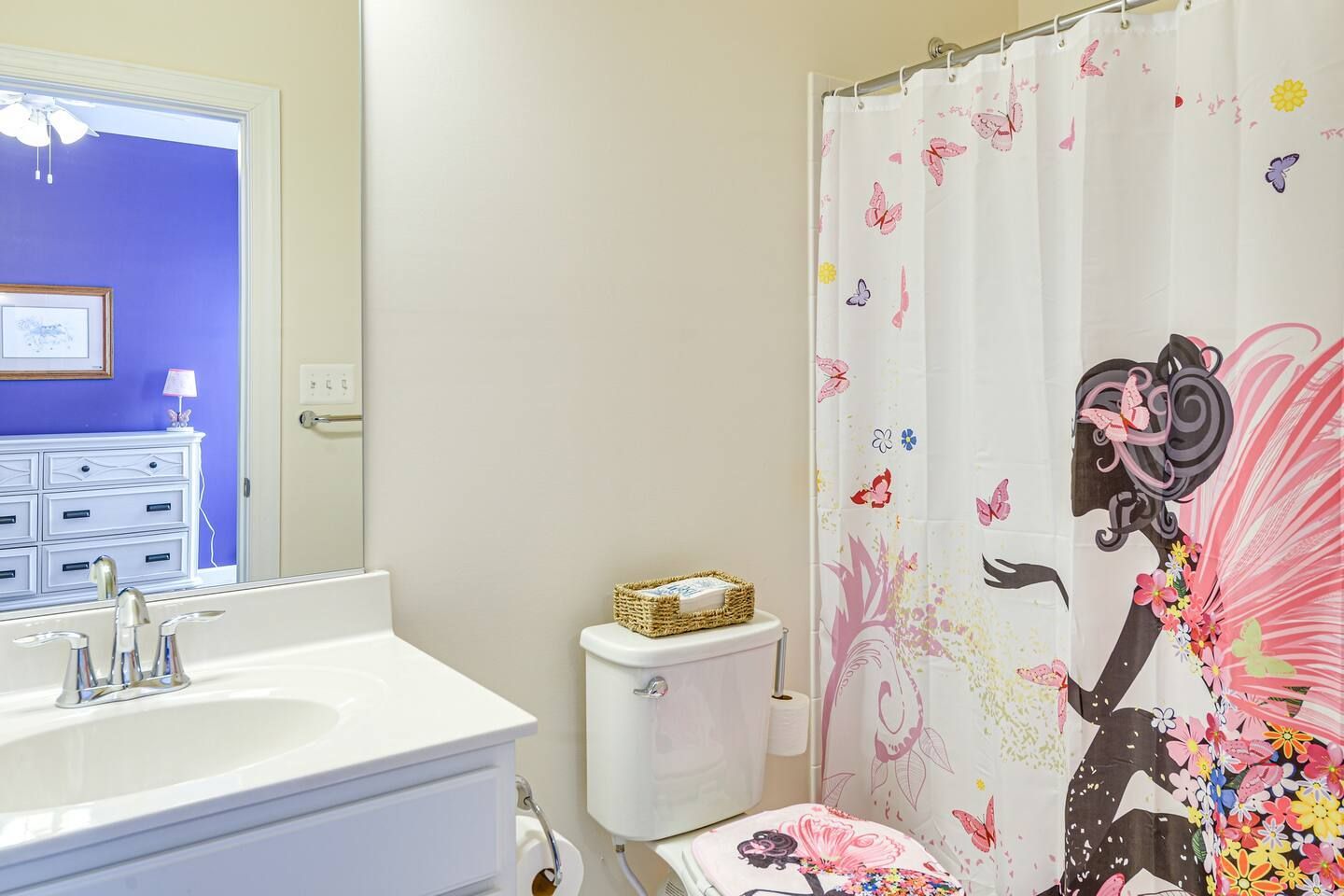 A bathroom with a toilet , sink , shower curtain and mirror.