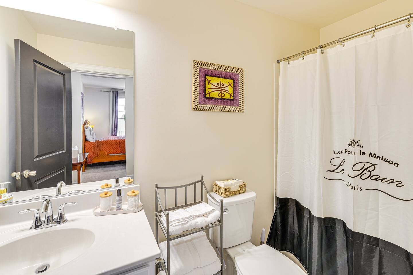 A bathroom with a sink , toilet , shower curtain and mirror.