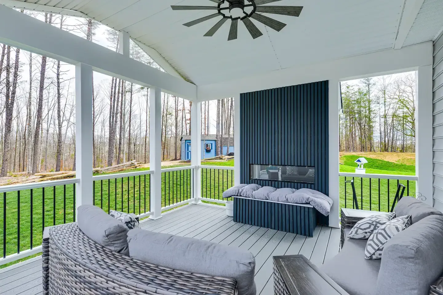 A screened in porch with a fireplace and a ceiling fan.