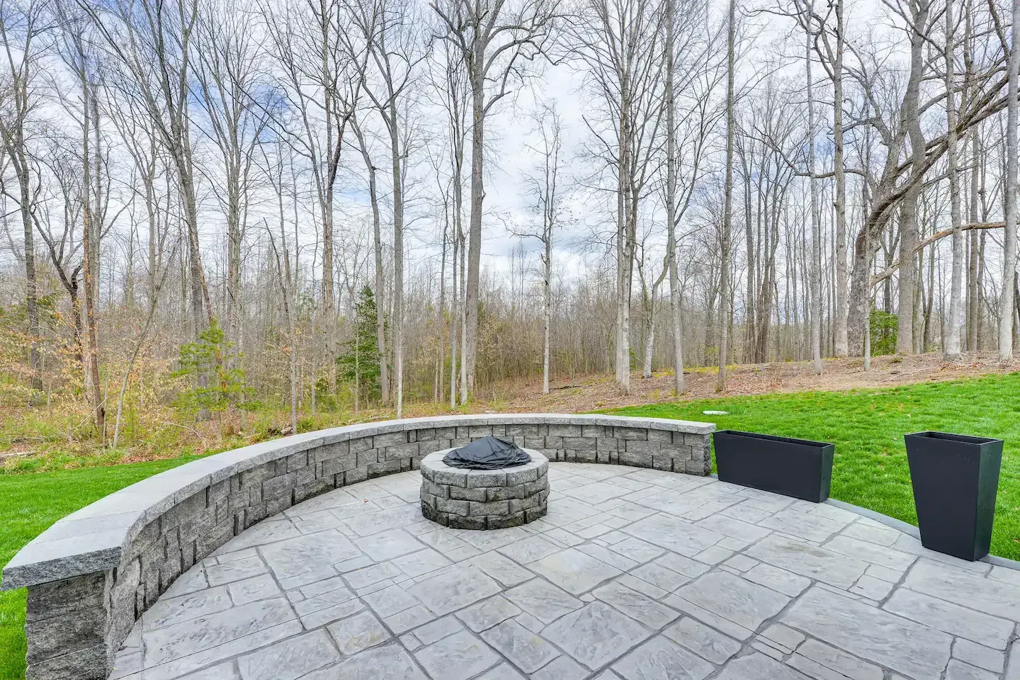 There is a fire pit on the patio in the middle of the woods.