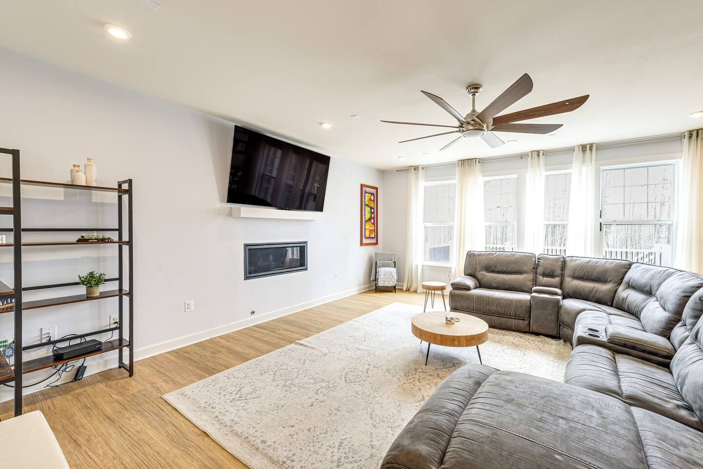 A living room with a couch , table , television and ceiling fan.