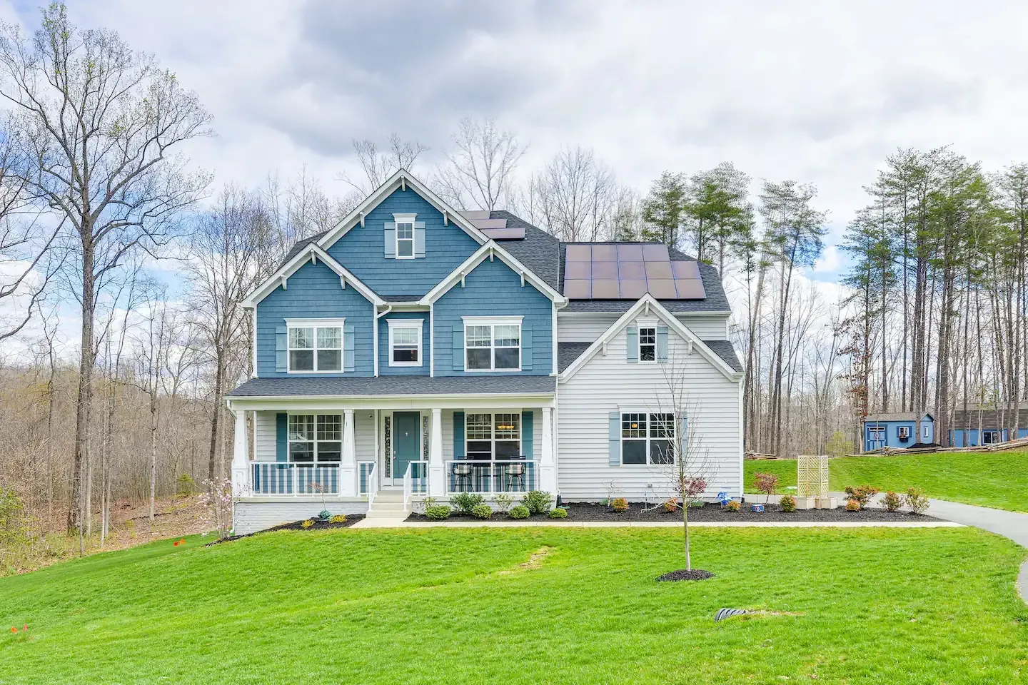 A blue and white house with a large lawn in front of it.