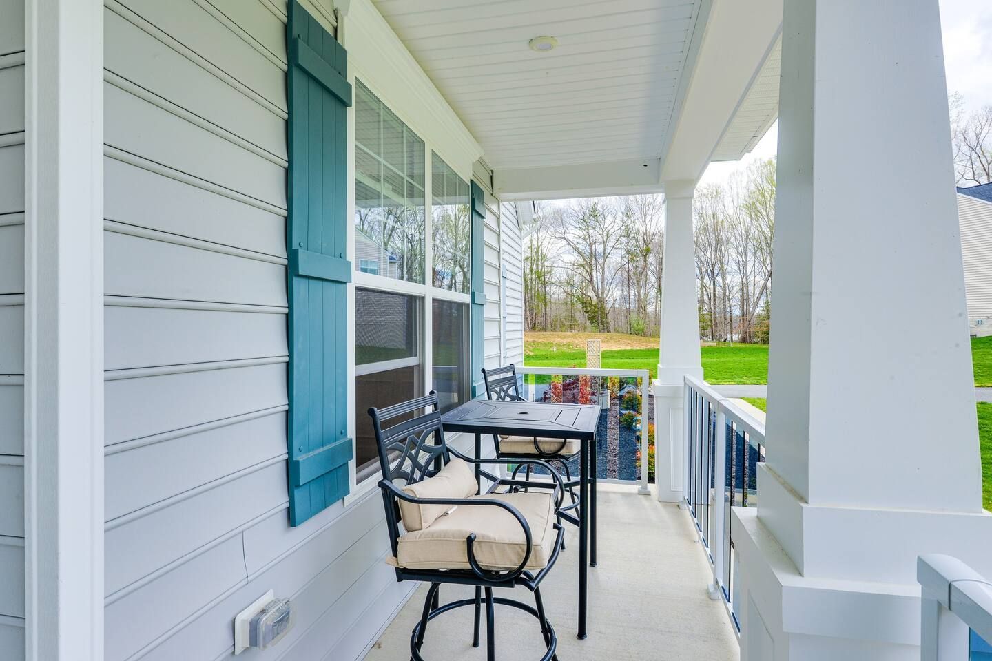 There is a porch with a table and chairs on it.