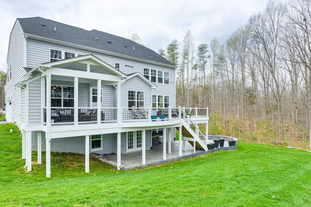 A large white house with a large deck in the backyard.