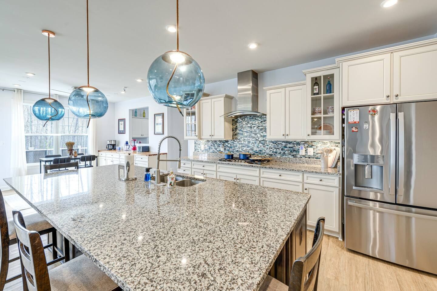 A kitchen with granite counter tops , stainless steel appliances , and white cabinets.