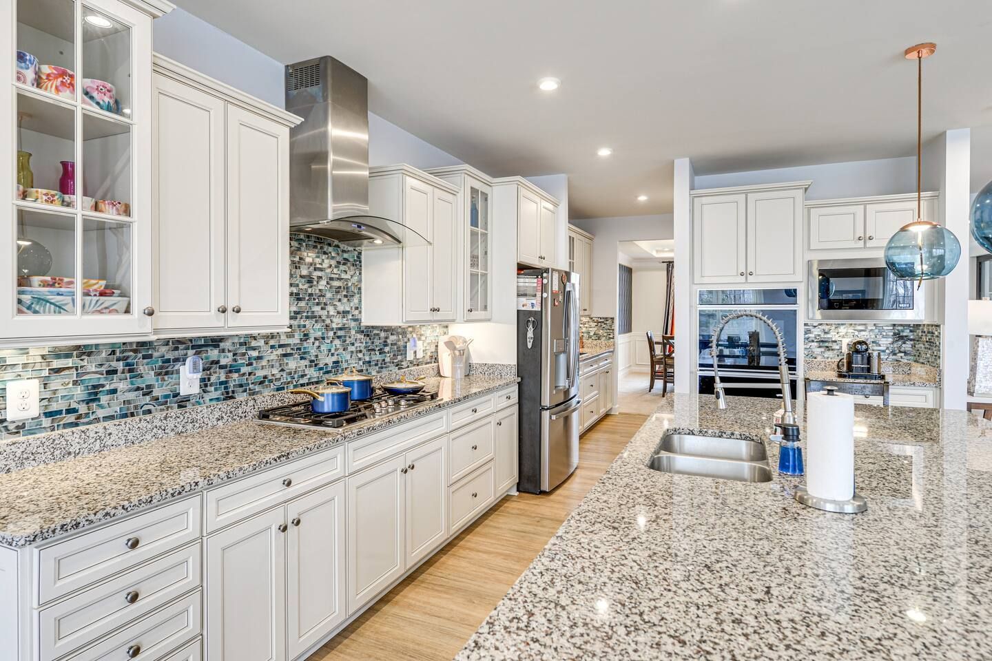 A kitchen with granite counter tops , white cabinets and stainless steel appliances.