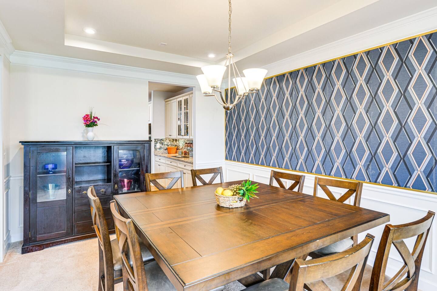 A dining room with a wooden table and chairs and a chandelier.